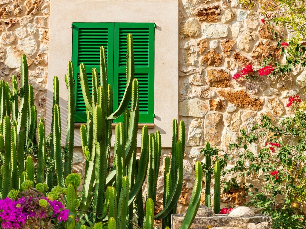 Casa mediterránea reformada en Mallorca con fachada de piedra y persianas verdes