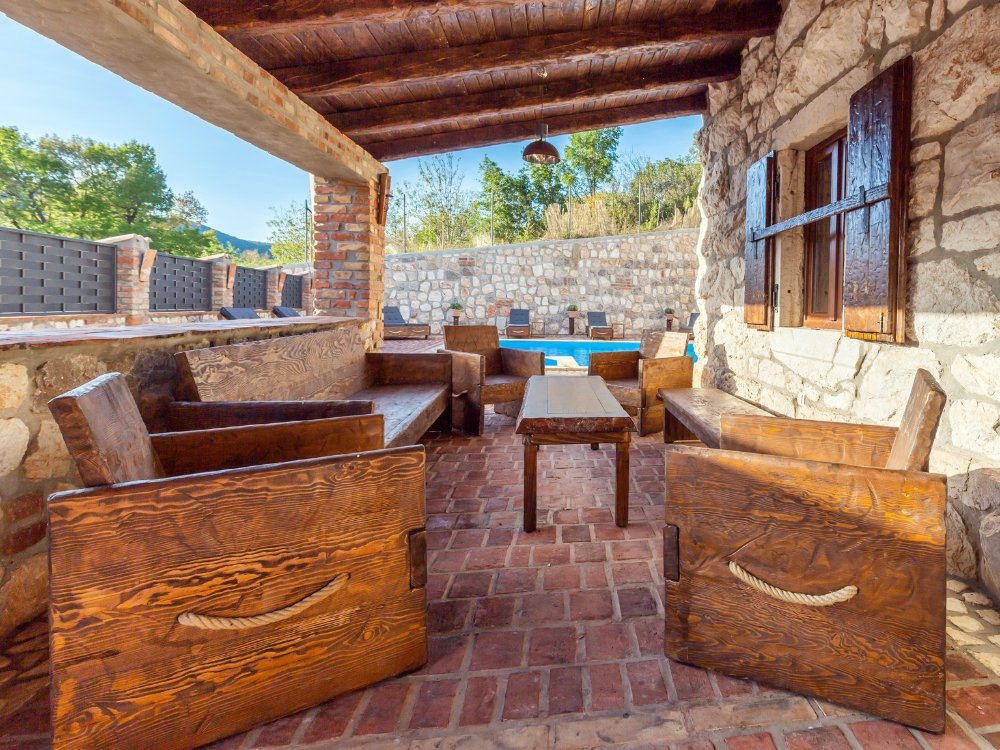 Zona exterior de vivienda mediterránea reformada en Mallorca con piedra natural, madera y espacio de descanso